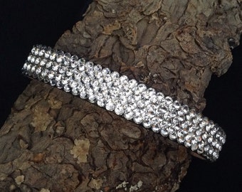 May include: A silver headband with three rows of clear rhinestones.