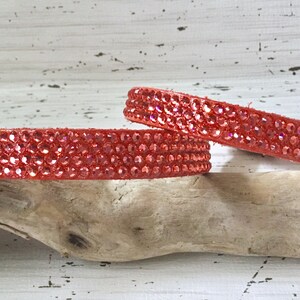 Puede incluir: Dos collares de cuero rojo con filas de brillantes piedras de cristal rojas.