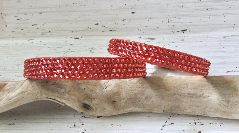 Puede incluir: Dos collares de cuero rojo con filas de brillantes piedras de cristal rojas.