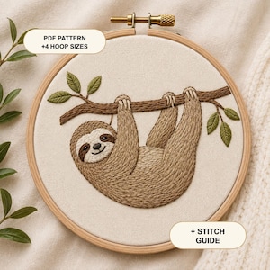 May include: A round wooden embroidery hoop containing a fabric panel with a stitched sloth hanging from a brown branch with green leaves. The image includes text labels reading PDF PATTERN +4 HOOP SIZES and + STITCH GUIDE on the cream fabric.