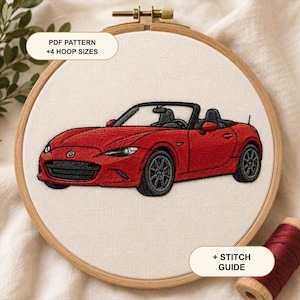Puede incluir: Un bastidor de bordado circular de madera que contiene un diseño de coche descapotable rojo cosido sobre tela blanca. El texto PDF PATTERN +4 HOOP SIZES y + STITCH GUIDE es visible. El coche tiene ruedas negras, interior negro y logo Mazda.