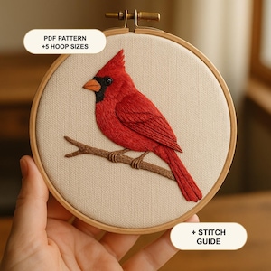 May include: A round wooden embroidery hoop containing a fabric panel with a detailed red cardinal bird stitched in thread, perched on a brown branch. The image includes text labels that read PDF PATTERN +5 HOOP SIZES and + STITCH GUIDE.