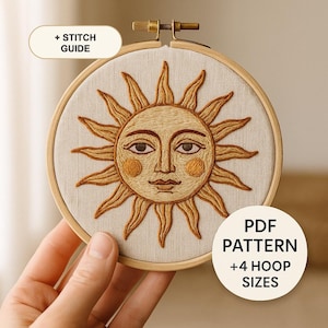 Puede incluir: Un bastidor de bordado circular de madera con tela color hueso y un diseño de cara de sol bordado en tonos amarillos y marrones. El texto dice + STITCH GUIDE y PDF PATTERN + 4 HOOP SIZES. El sol presenta rayos y mejillas sonrosadas.