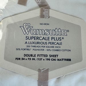 May include: A Wamsutta Supercale Plus double fitted sheet in white. The packaging label reads: No-Iron, A Luxurious Percale, 200 threads per square inch, 50% Fortrel polyester and 50% combed cotton, for a 54 x 75 inch mattress.