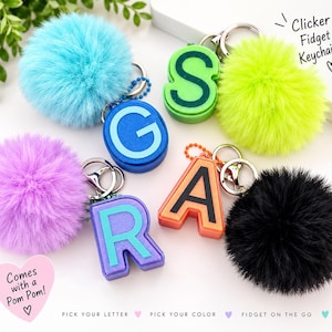 May include: Four letter-shaped clicker fidget keychains with attached fluffy pom-poms in light blue, neon green, purple, and black. The letters G, S, R, and A are featured in blue, green, purple, and orange. Text reads Clicker Fidget Keychains.