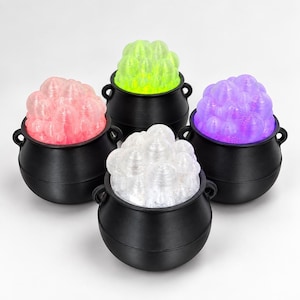 May include: Four black plastic cauldrons, each filled with a cluster of translucent, bubble-like spheres. The spheres are colored in bright pink, neon yellow, purple, and clear white, creating a vibrant contrast against the matte black pots.