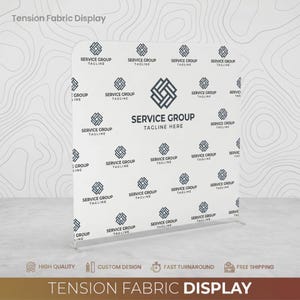 May include: A white tension fabric display featuring a repeating dark gray geometric logo pattern. The center displays the text SERVICE GROUP TAGLINE. The structure is a rectangular frame with rounded top corners, designed for professional event branding.