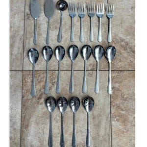May include: A collection of stainless steel flatware including two serving spatulas, one ladle, four dinner forks, seven solid spoons, and four slotted spoons. Each piece features a simple, smooth handle design with a polished metallic finish.