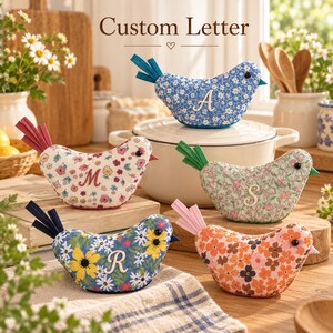 Puede incluir: Cinco adornos de pájaros de tela con estampados florales en azul, crema, verde y naranja. Cada pájaro tiene una cola de fieltro, un pequeño ojo de cuenta negra y una letra blanca bordada en el costado. Las letras mostradas son A, M, S y R.