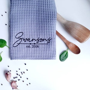 May include: A gray waffle weave kitchen towel with the text "Swansons est. 2006" embroidered in black.