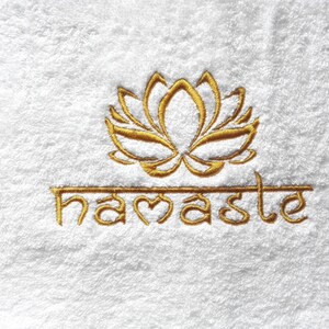 May include: White towel with gold embroidered lotus flower and the word "namaste" below it.
