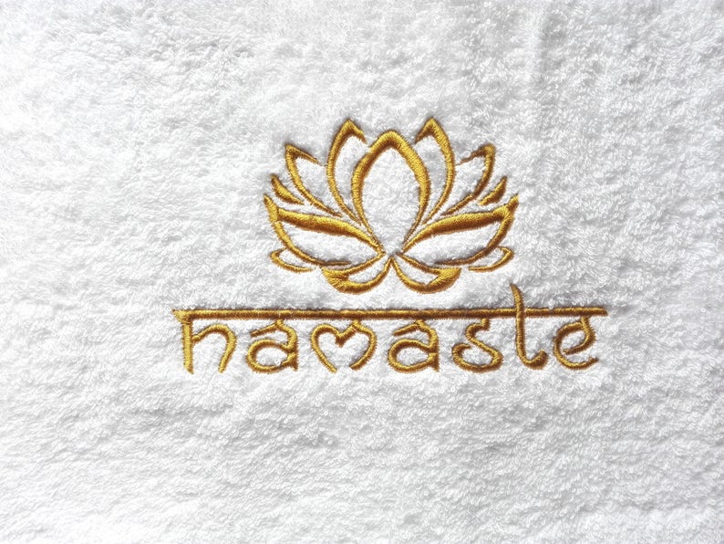 May include: White towel with gold embroidered lotus flower and the word "namaste" below it.