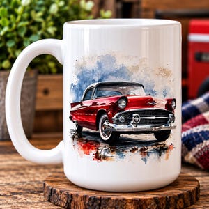 May include: A white ceramic mug featuring a watercolour-style illustration of a vintage red car with chrome accents. The car is depicted against a backdrop of blue and tan paint splashes, showcasing a classic front grille, round headlights, and white-wall tyres.