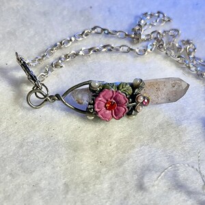 Crystal pendant with metal floral embellishment.  On silver tone chain. approximately 20”.