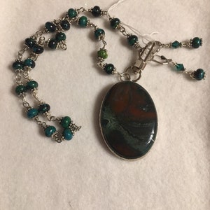 Natural Stone pendant in shades of green and burnt orange wrapped in silver.  pendant on wire wrapped necklace of green stone beads- set