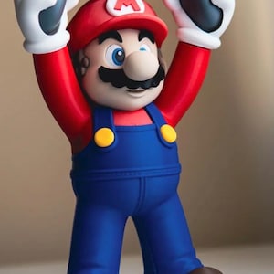 May include: A figurine of a character wearing a red cap with a white M, a red shirt, blue overalls with yellow buttons, and brown shoes. The character is holding a gray video game controller with white, red, blue, and green buttons above its head.