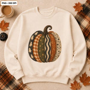 May include: A cream-coloured crewneck sweatshirt featuring a large, central graphic of a pumpkin. The pumpkin is divided into vertical segments, each displaying different patterns including ghosts, orange plaid, green stars, blue waves, moons, and floral vines.