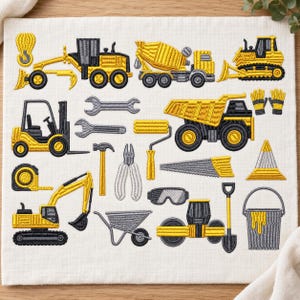 Puede incluir: Un panel de tela blanca con bordados a máquina en amarillo y gris de vehículos y herramientas de construcción, incluyendo una grúa, hormigonera, excavadora, carretilla elevadora, camión volquete, retroexcavadora, carretilla, rodillo y varias herramientas.