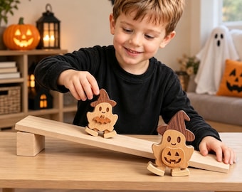 May include: Two wooden ghost figurines with dark brown hats, one holding a small bat and the other a jack-o'-lantern, positioned on a light-colored wooden ramp. The ghosts have carved facial features and are crafted from light and dark wood tones.