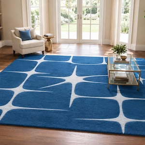 May include: A large rectangular area rug featuring a deep blue background with a repeating white starburst or geometric grid pattern. The rug has a low-pile texture and covers a significant portion of the floor, showcasing a bold contrast between the blue and white colors.