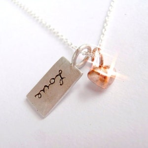 May include: A silver necklace with a rectangular tag that says "love" and a small copper heart charm.