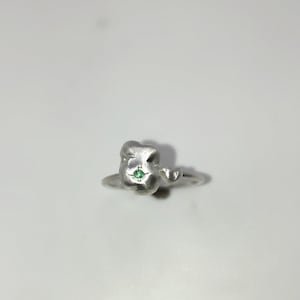 May include: A silver ring with a green gemstone set in a textured, irregular shape.