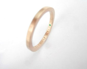 Könnte beinhalten: Ein schlichter Roségold-Bandring mit einem kleinen grünen Edelstein, der seitlich eingefasst ist. Der Ring ist mit den Worten "14K YISELY 4.1." graviert.