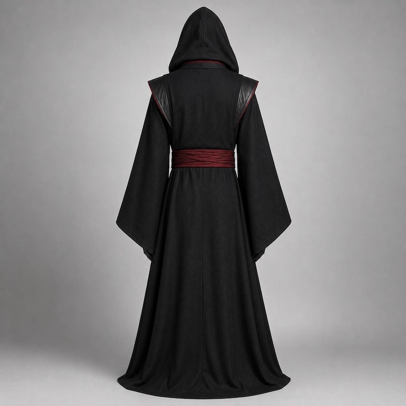 May include: A floor-length black hooded robe featuring wide, flared sleeves and a dark red horizontal waistband. The garment has structured shoulder panels and a pointed hood, presented from a rear-facing perspective against a neutral background.