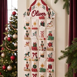 Peut inclure: Un calendrier de l'Avent en tissu couleur crème suspendu au mur, portant le prénom Oliver en lettres rouges. Il comporte vingt-quatre poches numérotées ornées d'illustrations colorées de casse-noisettes, de cadeaux, d'étoiles et de motifs festifs.