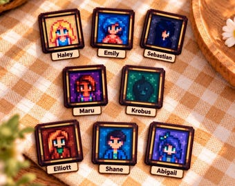 Op de afbeelding: Acht vierkante houten pins met pixel art portretten van Stardew Valley personages. Elke pin toont een uniek personage met een naamplaatje eronder, waaronder Haley, Emily, Sebastian, Maru, Krobus, Elliott, Shane en Abigail.