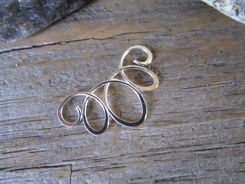 May include: Silver swirl design earring, a delicate and intricate piece of jewelry.