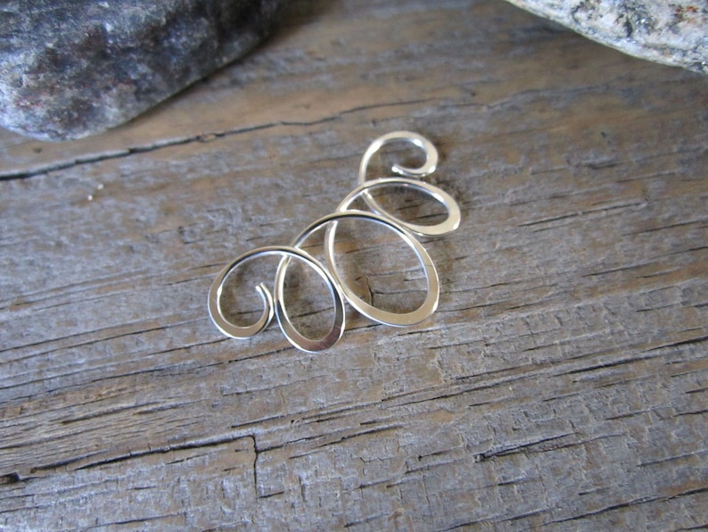 May include: Silver swirl design earring with multiple loops.
