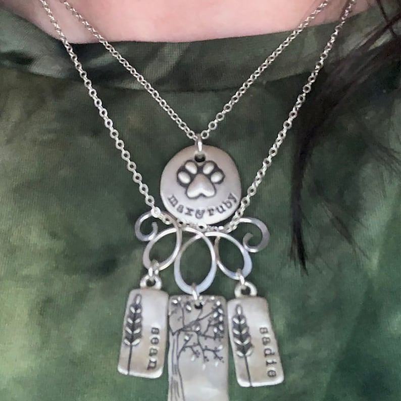 May include: Silver necklace with a paw print charm that says "Max & Ruby" and three charms that say "Bean", "Sadie", and a tree with branches.