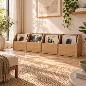May include: A light-toned wooden vinyl record storage unit featuring four open-front compartments. Each section holds multiple vinyl records, including albums by Norah Jones, The Beatles, Fleetwood Mac, and Tyler, the Creator, displayed upright.