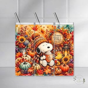 Może przedstawiać: Cylindryczny kubek ze słomką z akwarelową ilustracją Snoopy'ego w dzianinowej czapce, trzymającego kubek z napisem Hello Fall, w otoczeniu dyń, słoneczników, jesiennych liści oraz latarni z napisem Happy Fall Y'all.