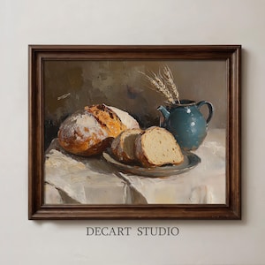 May include: An oil painting in a dark wood frame depicting a loaf of bread, two slices of bread on a plate, and a teal pitcher with wheat stalks. The text DECART STUDIO is printed at the bottom. The scene features warm brown and cream tones.