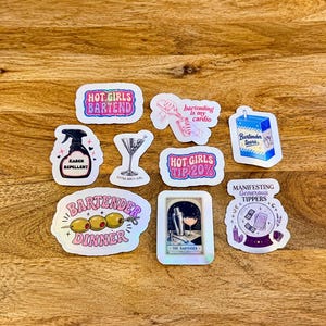 May include: A collection of nine vinyl stickers featuring bartending themes. Designs include text such as HOT GIRLS BARTEND, Bartending is my cardio, HOT GIRLS TIP 20%, KAREN REPELLENT, BARTENDER DINNER, and MANIFESTING GENEROUS TIPPERS, alongside illustrations of cocktails and a tarot card.