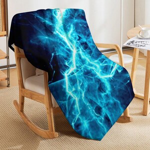 May include: A rectangular throw blanket featuring a vibrant, high-contrast graphic print of bright electric blue lightning bolts against a deep navy and black background. The design displays intricate, branching light patterns across the fabric.