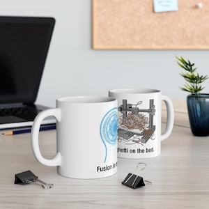 Könnte beinhalten: Zwei weiße Keramiktassen mit 3D-Druck-Grafiken. Eine Tasse zeigt ein blaues Drahtgitter-Zahnrad mit dem Text Fusion in my head. Die andere Tasse zeigt einen 3D-Drucker mit einem Gewirr aus Filament und dem Text Spaghetti on the bed.
