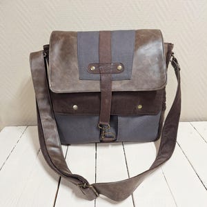 Peut inclure: Sac messager avec fermeture à rabat, combinant cuir marron, toile grise et velours côtelé. Il possède une longue bandoulière réglable et une fermeture à boucle. Le design inclut une sangle verticale en cuir avec des rivets en laiton.