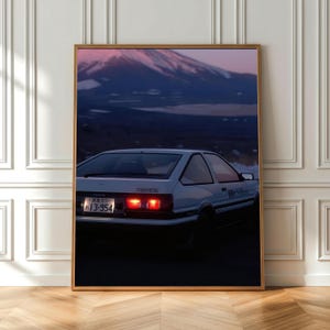 May include: A white Toyota AE86 hatchback with black trim and illuminated red taillights, parked against a backdrop of a mountain at dusk. The Japanese license plate reads 13-954, and the side panel features Japanese text in black lettering.