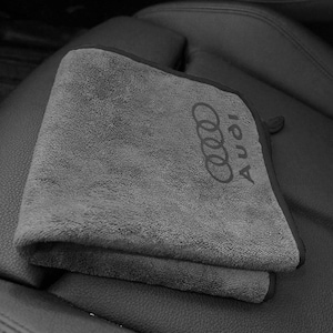 Peut inclure: Un chiffon en microfibre gris plié avec une bordure gris foncé et le logo Audi brodé en fil gris foncé assorti sur le coin. Le tissu présente une texture douce et pelucheuse, de forme rectangulaire avec des coins arrondis.