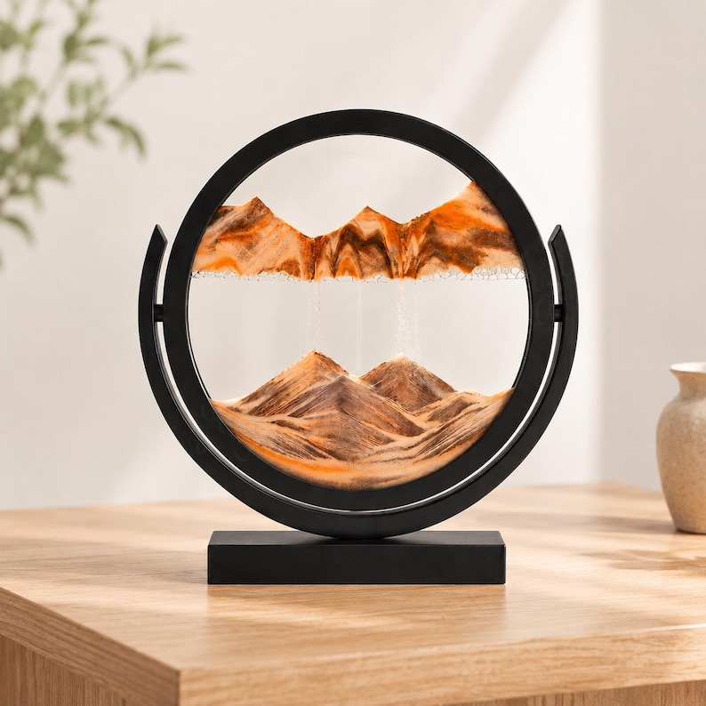 Orange and amber 3D moving sand art showing desert mountain landscape, warm-toned tabletop decor.
