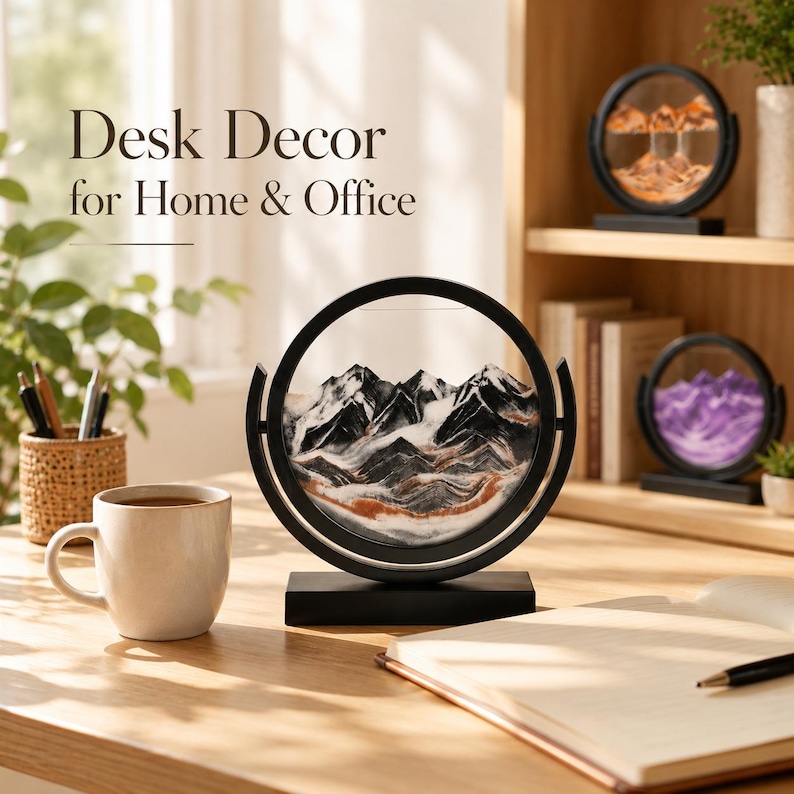 May include: A circular black frame containing layered sand art that forms a mountain landscape with black, white, and copper-colored sand. The text Desk Decor for Home & Office is visible in the upper left corner of the image.