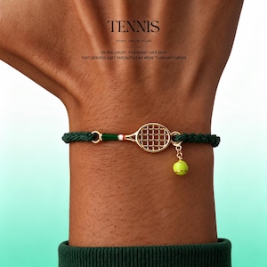 May include: A dark green braided cord bracelet featuring a gold-tone tennis racket charm with green, white, and red accents, and a small lime green tennis ball charm hanging from the racket head. The text TENNIS SPORTS JEWELRY DESIGN is visible.