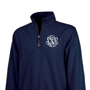 May include: A navy blue quarter-zip sweatshirt with a white monogram on the chest.