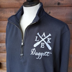 May include: Black quarter-zip sweatshirt with a white embroidered logo featuring crossed oars and the text "LAKE" and "Daggett".