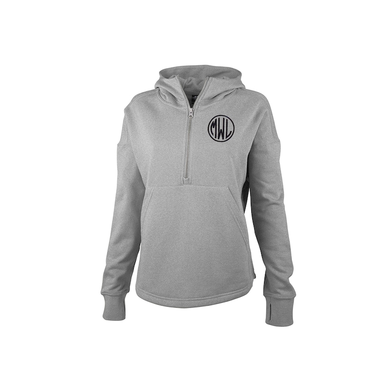 May include: A light gray hooded sweatshirt with a quarter-zip closure and a kangaroo pocket. The sweatshirt features a black circular monogram with the letters "MWL" on the upper chest. The sleeves have thumb holes at the cuffs.