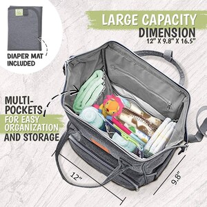 K&ouml;nnte beinhalten: Eine graue Wickeltasche mit mehreren Taschen f&uuml;r Organisation und Aufbewahrung. Die Tasche ist offen und mit Babyartikeln gef&uuml;llt, darunter eine Wickelunterlage, Feuchtt&uuml;cher, Flaschen und Spielzeug. Die Tasche misst 30,5 cm x 24,9 cm x 41,9 cm.