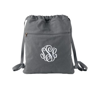 May include: A gray drawstring backpack with a zippered pocket and a white embroidered monogram. The monogram is a circle with the letters "S S C" inside.